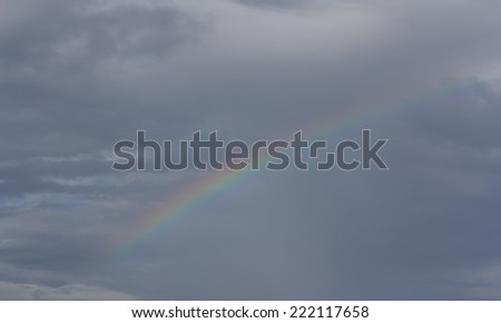 Rainbow in the sky against dark clouds and a rain