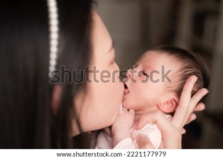 lifestyle shot on young and happy Asian Chinese woman holding tenderly her adorable newborn baby girl in her arms in mother and daughter love and care concept