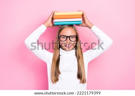 Photo of cheerful smart girl arms hold pile stack book head toothy smile isolated on pink color background