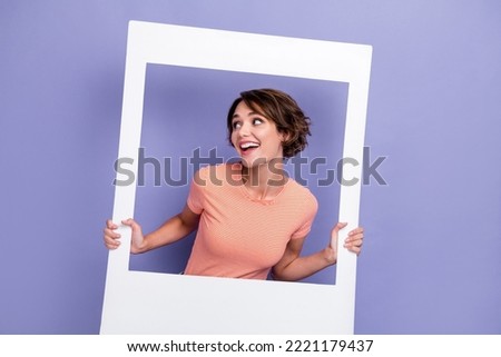 Photo of cheerful pretty lady wear stylish clothes interested look empty space hand hold paper frame isolated on purple color background