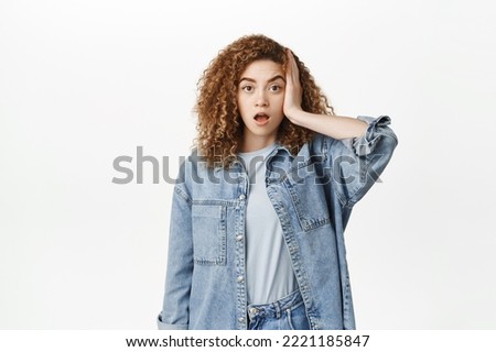 Portrait of shocked and troubled woman facepalm, looking alarmed and worried, remember or forgot smth, standing over white background