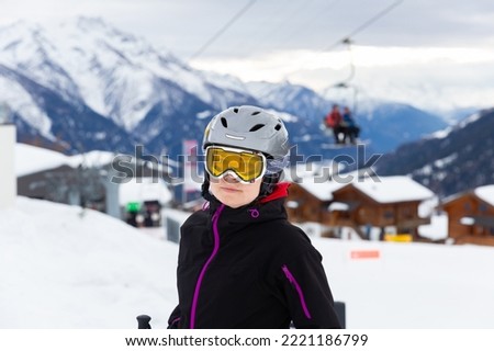 Closeup portrait of positive woman in ski helmet and glasses enjoying vacation in alpin ski resort on sunny winter day. Active holidays concept