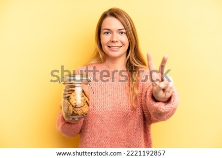 pretty blonde young woman smiling and looking friendly, showing number two. home made cookies concept