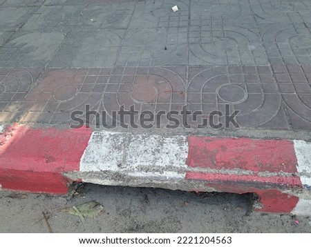 The edge of the pavement painted with a red and white warning sign indicates that it is forbidden to park as a sidewalk on the side of the road in the old way.