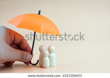 Insurance concept. Wooden family peg dolls with umbrella. Family, life, travel and health insurance. Orange background with copy space Royalty-Free Stock Photo #2221206655