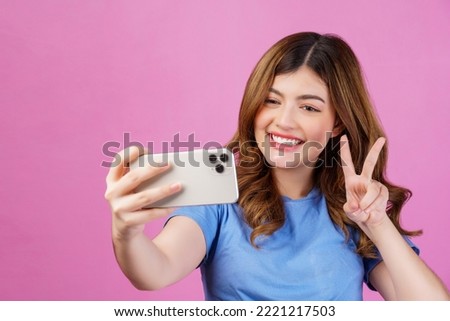 Portrait of happy smiling young woman wearing casual t-shirt selfie with smartphone isolated over pink background. Technology, people and lifestyle concept.