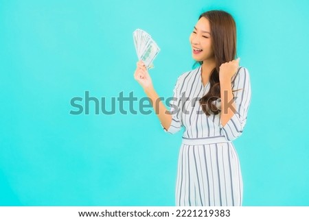 Portrait beautiful young asian woman with a lot of cash and money on blue background