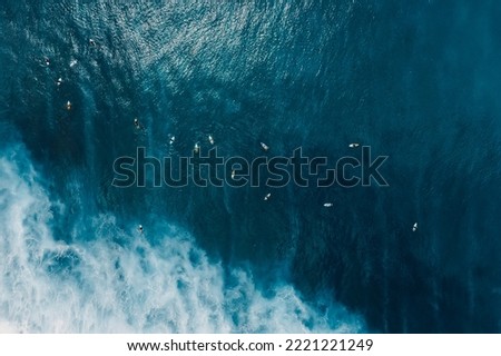 Aerial view of surfers in blue ocean with waves at Bali island. Top view