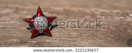 St. George's ribbon and the Order of the Red Star of the USSR World War II veteran on a wooden background. Translation into Russian: Workers of all countries unite. The concept of the May 9 holiday.