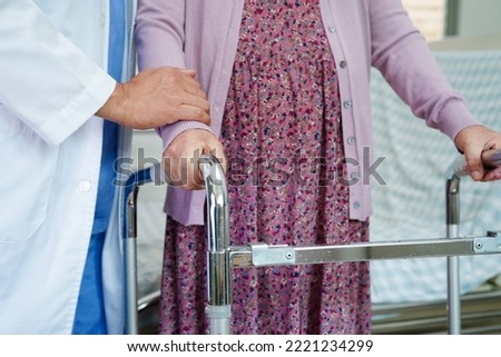 Doctor help Asian elderly woman disability patient walk with walker in nursing hospital, medical concept.