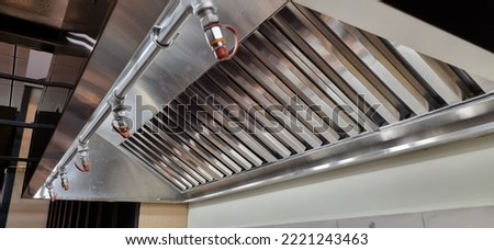 Stainless Steel shiny exhaust hood with grease baffles and fire suppression system Royalty-Free Stock Photo #2221243463