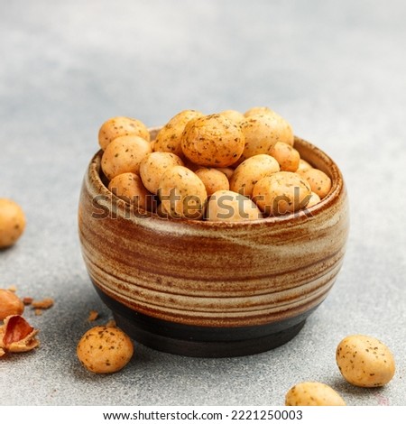 Crispy Nuts. Peanuts in glaze with seasonings and spices. A delicious snack for beer. Grey concrete background. Selective focus, top view, copy space, square picture