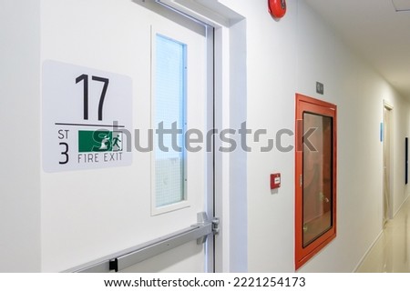 Fire extinguisher system on the wall with Fire Exit door sign for emergency. Stairwell fire for escape in building or apartment