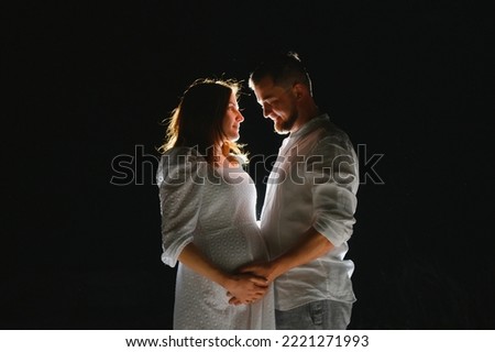 Happy Pregnant Couple. Mother and Father Love expecting Baby during Pregnancy. Family waiting Child Birth over Black night Background.