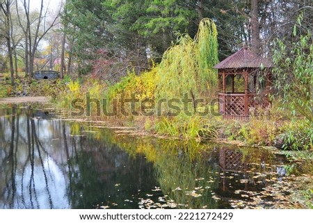 Pond in the autumn forest with a wooden gazebo