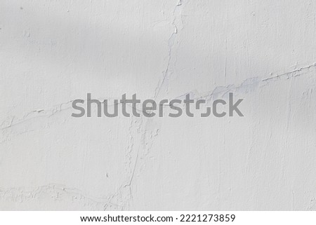 A photo of a white wall with cracks coming together.