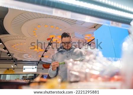 Man looking for vegetable Male Customers Shopping in the foreground are shelves in a store