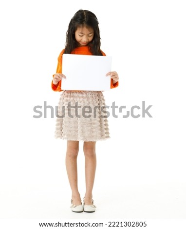 Portrait full body cutout isolated studio shot of Asian young happy primary schoolgirl model in casual outfit standing holding advertising placard paper board for text copy space on white background.