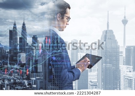  attractive thoughtful european businessman using pad with creative candlestick forex chart index hologram on blurry background. Trade, business market and finance analysis concept. Double exposure