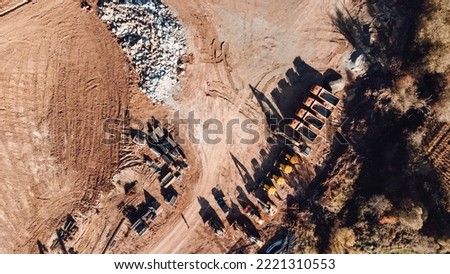 Aerial view of excavators, bulldozers and dumper trucks at highway construction site. Industrial machinery at construction site