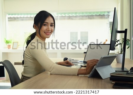 Charming female graphic designer working with modern devices at bright office