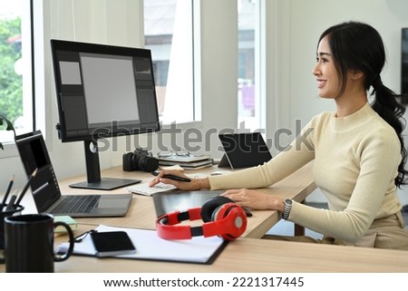 Attractive female photo editors sitting in creative workplace and retouching photos on personnel computer