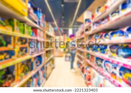 Blur toy store interior as background with copy space. Defocused shelves with many toys. Blurred teenage boy choosing birthday gift at toy market 