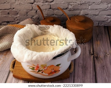 Cooking preparation of homemade cottage cheese or cheese curd product. The process of draining filtration of curdled milk and separation of whey by cheesecloth. Royalty-Free Stock Photo #2221330899