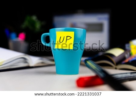 Sticky note on a coffe cup at office desk. Wake up concept