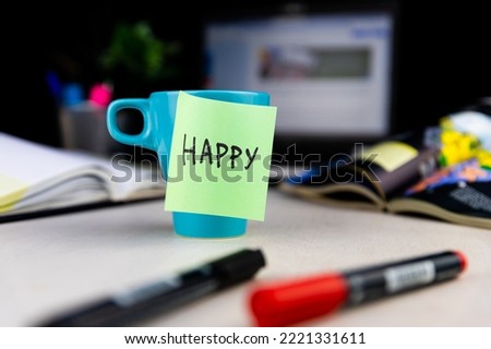 Sticky note with word Happy on a cup of coffee at the office desk. Every morning wake up with the smile