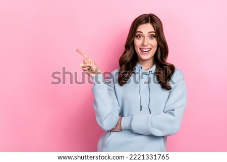 Photo of positive cheerful person beaming smile indicate finger empty space isolated on pink color background