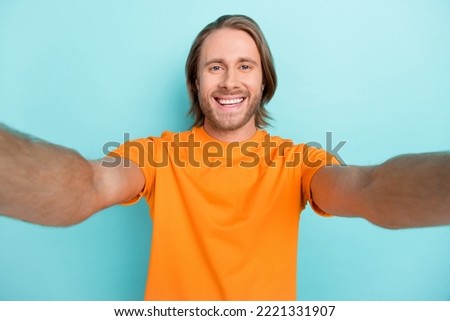 Selfie closeup photo of young attractive handsome smiling man wear orange t-shirt no brand positive blogger isolated on blue color background