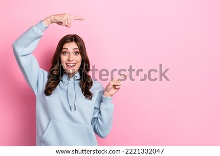 Photo of positive pretty girl beaming smile indicate fingers empty space isolated on pink color background