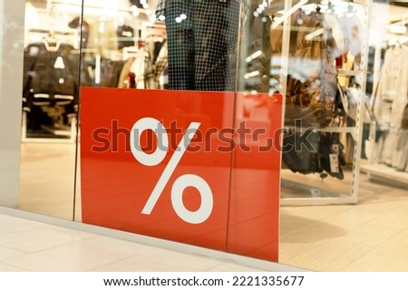 A large red banner behind the glass of the showcase, a banner with a mark of interest. In the store the season of discounts, promotions, sales, Black Friday. Favorable prices in the clothing store.
