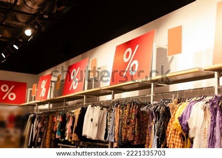 Clothing store with large red discount banners in the window. Photo of a clothing store in a shopping mall. Discount, promotions, sales in shopping centers and shops. Royalty-Free Stock Photo #2221335703