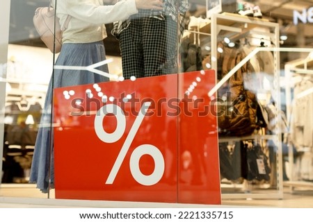 On the showcase there is a large red banner with a discount.The seller or buyer looks at the mannequin clothes.