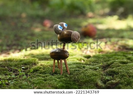 Cute figure made of acorns on green moss outdoors,