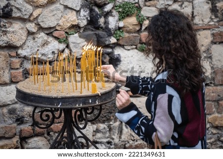 Woman lights the candle in Serbian orthodox church. Royalty-Free Stock Photo #2221349631