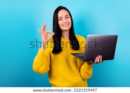 Portrait of attractive cheerful skilled girl using laptop showing ok-sign  isolated over bright blue color background
