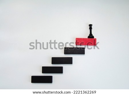 Black chess piece on red wooden block on white. Business planning, Risk Management, Solution, leader, strategy, Unique Concepts. Wood block stacking as step stair. Concept for business growth