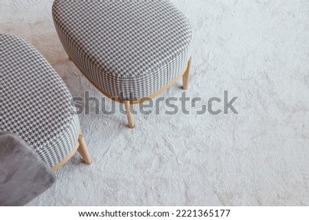 Checkered armchair with bench on wooden legs on a fluffy carpet, top view with copy space Royalty-Free Stock Photo #2221365177