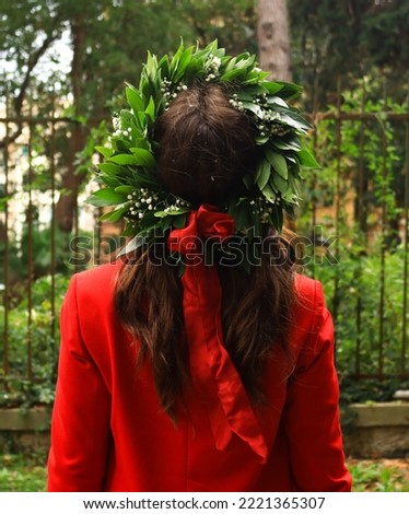 Degree of a wonderful engineer in a red suit with her laurel crown. Shooted in a italian green park with a little wind. Congratulation! Royalty-Free Stock Photo #2221365307