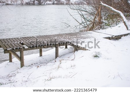 a snowy wooden wharf by the river