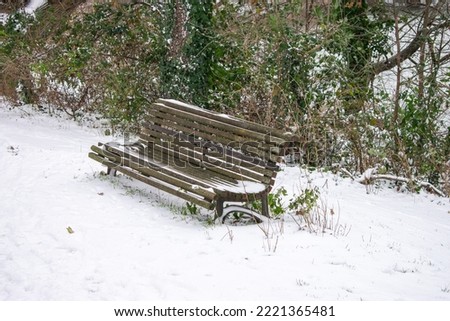 a wooden bench in park with snow in winter