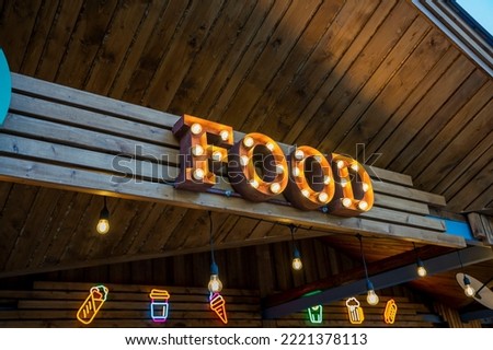 the glowing street sign of the FOOD street cafe. a beautiful sign illuminated by warm lamps on a wooden background