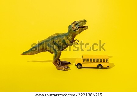 Toy t rex with school bus on a yellow background.