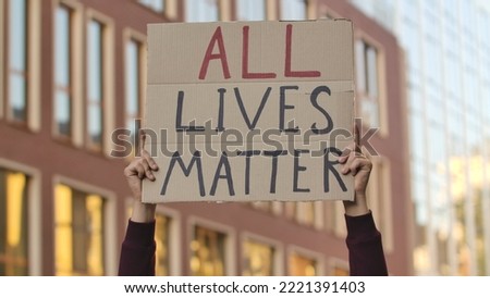 ALL LIVES MATTER on cardboard poster in hands of male protester activist. Stop Racism concept, No Racism. Rallies against racism and police brutality. Peaceful life of blacks matters. Close up.