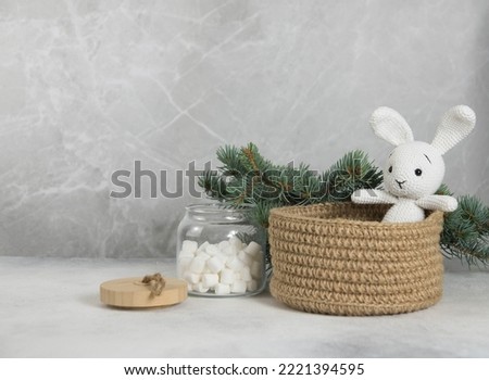 Christmas decoration of Knitting white toy hare is in knitting basket in light background.
