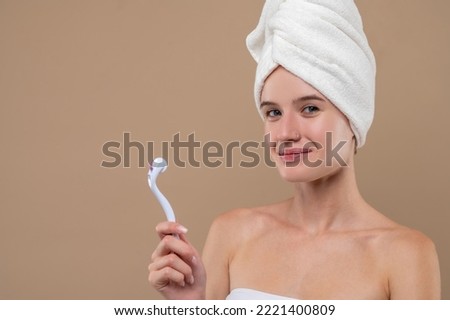 Girl holding a face roller and looking contented