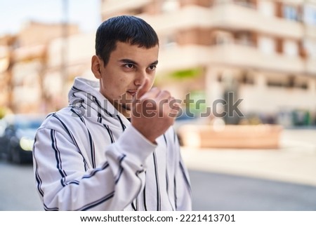 Young man smiling confident doing coming gesture with hand at street